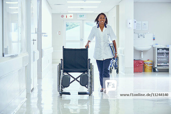 Weibliche Pflegerin schiebt Rollstuhl den Krankenhauskorridor entlang