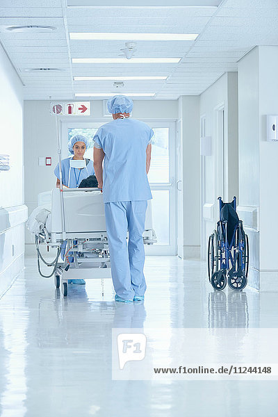 Male and female nurses pushing bed on hospital corridor