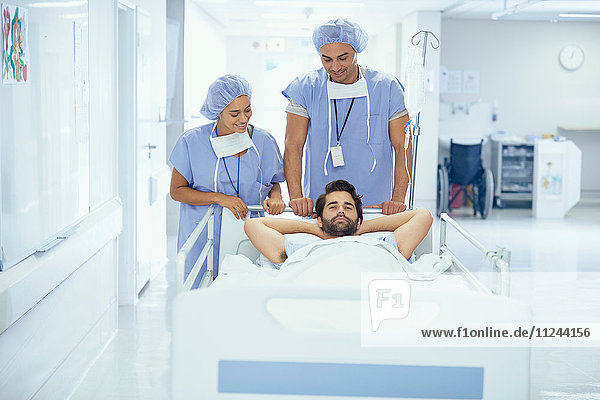 Junger männlicher Patient im Krankenhausbett  der von Krankenschwestern geschoben wird
