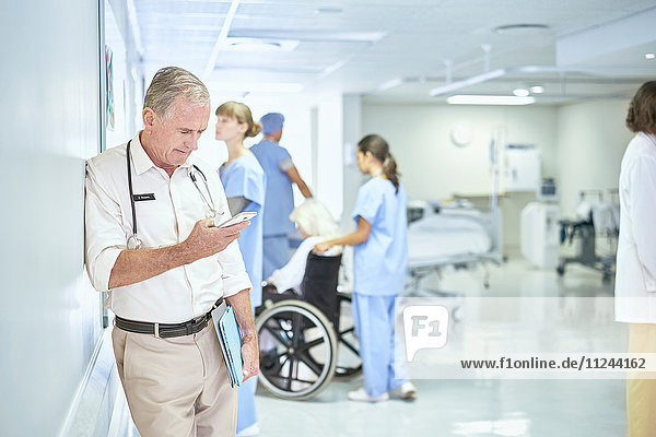 Leitender Arzt liest Smartphone-Nachricht auf der Krankenhausstation