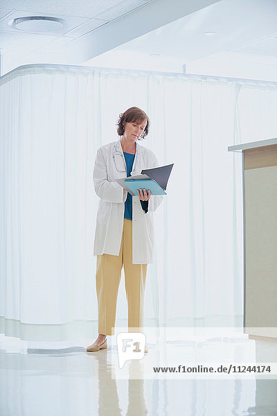 Ärztin liest medizinische Notizen auf der Schwesternstation im Krankenhaus