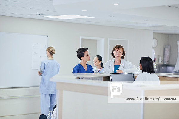 Female doctor having discussion with nurses at nurses station in hospital