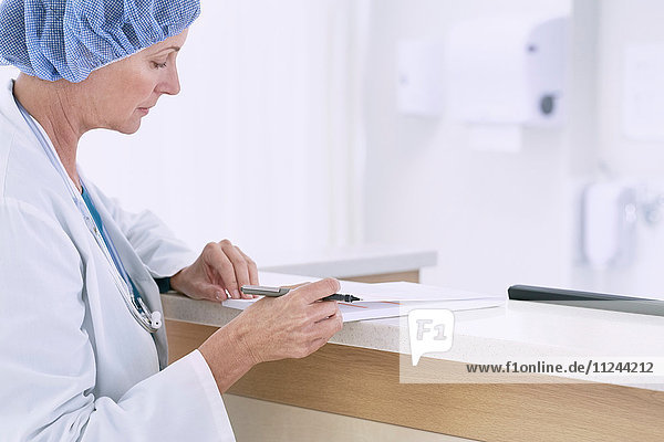 Ärztin schreibt medizinische Notizen auf der Schwesternstation im Krankenhaus