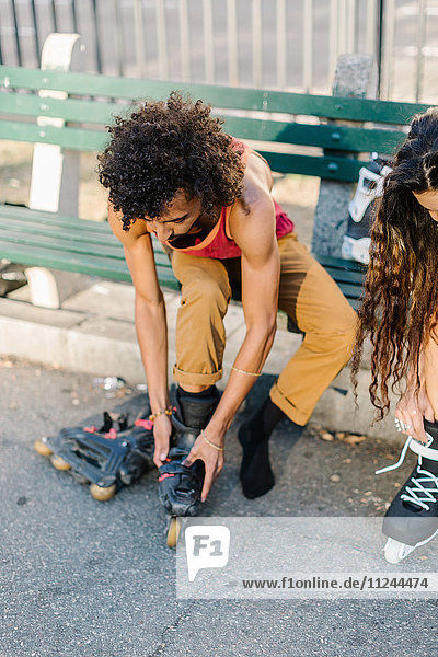 Junges Paar auf Parkbank beim Rollerbladen