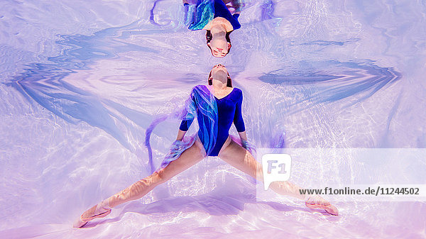 Unterwasseraufnahme eines Mädchens in blauem Trikot und Ballettschuhen mit Blick auf die Wasseroberfläche