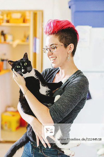Junge Frau mit rosa Trägerin einer Katze mit großen Augen in der Küche