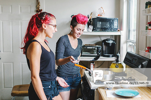 Zwei junge Frauen bereiten Essen auf dem Küchenherd zu