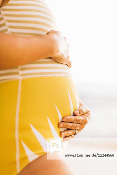 Mittlerer Abschnitt einer schwangeren  mittleren erwachsenen Frau mit Bauchhaltung Makua Beach  Hawaii  USA