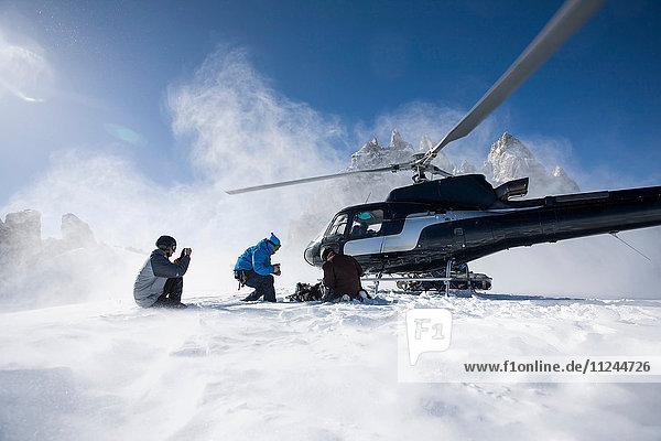 Three male snowboarders exiting helicopter  Trient  Swiss Alps  Switzerland