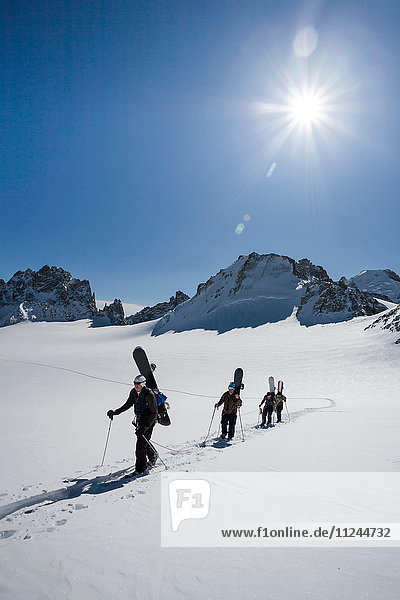 Four male snowboarders hiking across snow-covered landscape  Trient  Swiss Alps  Switzerland