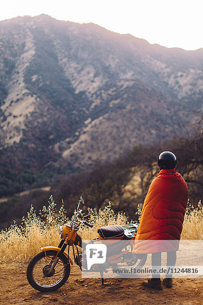 Man standing beside motorbike  wrapped in blanket  looking at view  rear view  Sequoia National Park  California  USA