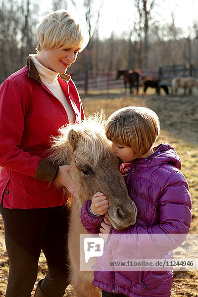 Porträt von Mutter und Tochter im Freien  stehend mit Pony