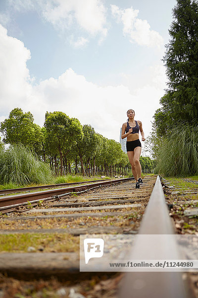 Frau joggt auf Eisenbahnschienen