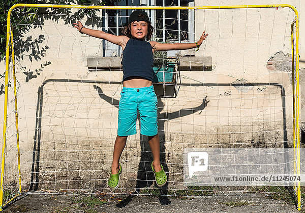 Junge im Fussballtor springt in die Luft