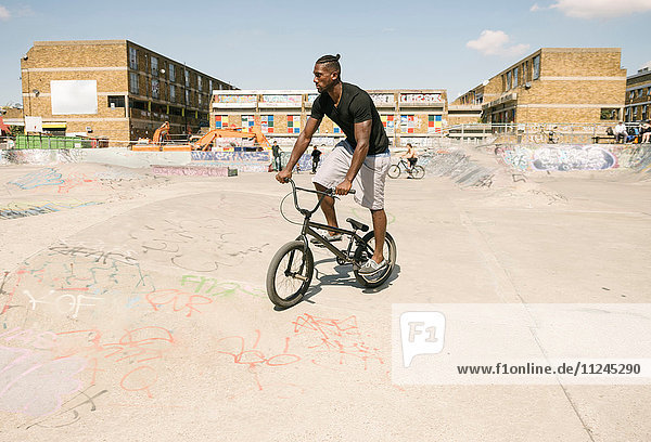 Young man riding BMX bicycle in skatepark