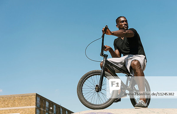 Junger Mann auf BMX-Fahrrad schaut sich im Skatepark über die Schulter