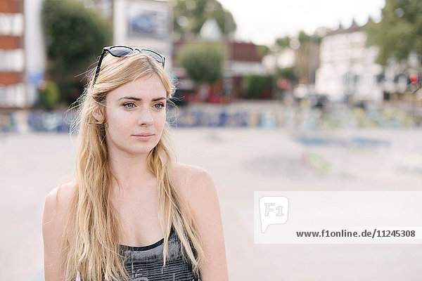 Porträt einer jungen Skateboarderin mit langen blonden Haaren im Skatepark