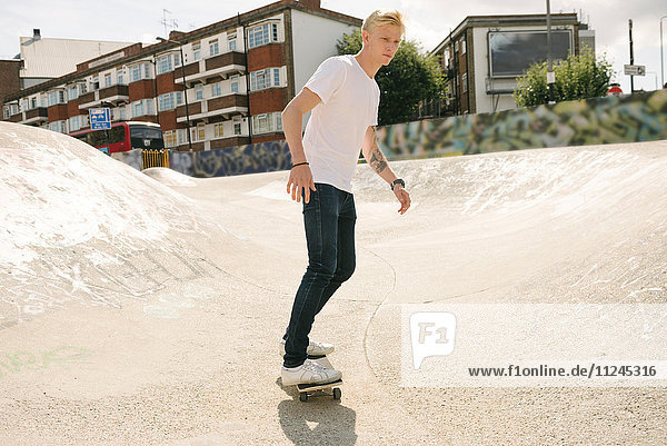 Young male skateboarder skateboarding in skatepark