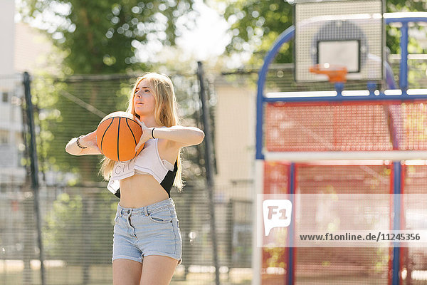 Junge Frau übt auf dem Basketballplatz