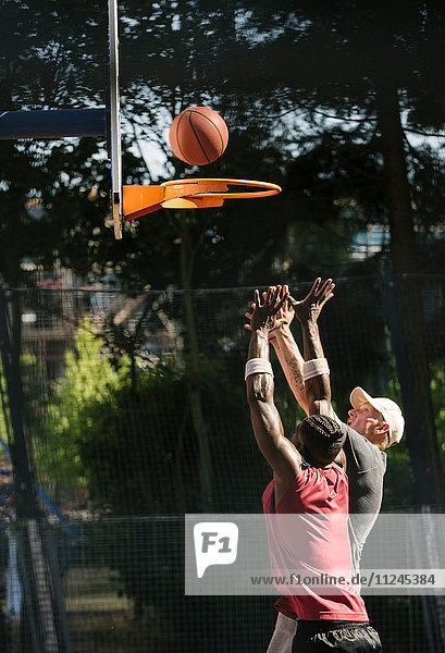 Junge männliche Basketballspieler werfen Ball auf Basketballkorb