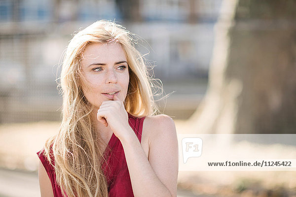 Portrait of pretty young woman with long blond hair in park