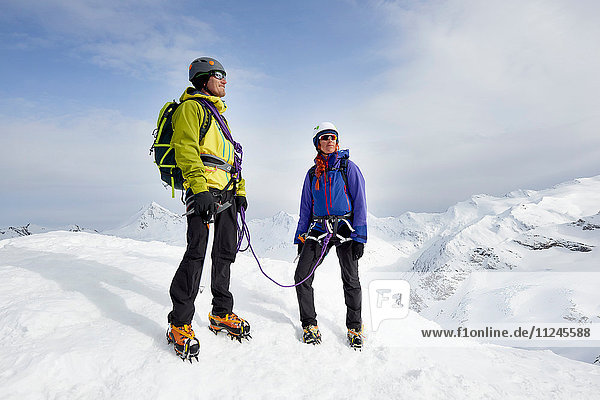 Bergsteiger auf dem Gipfel eines schneebedeckten Berges mit Blick in die Ferne  Saas Fee  Schweiz