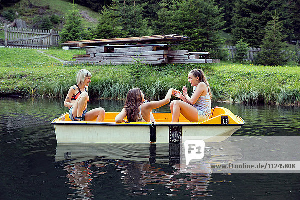 Drei erwachsene Freundinnen amüsieren sich im Ruderboot auf dem See  Sattelbergalm  Tirol  Österreich