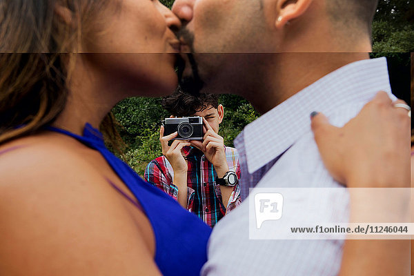 Reifes Paar im Freien  küsst sich  der Sohn fotografiert sie mit der Kamera