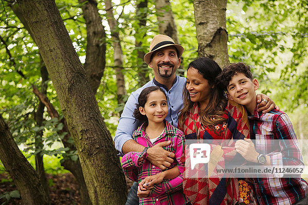 Porträt einer Familie  die im Wald steht und lächelt