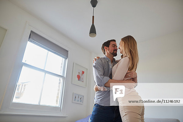 Mittelgroßes erwachsenes Paar umarmt sich im Wohnzimmer