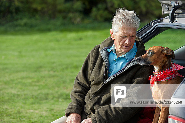 Man and dog sitting in car boot