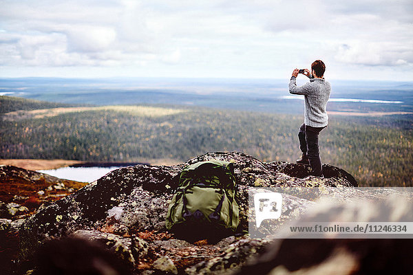 Wanderer beim Fotografieren auf dem Klippengipfel  Keimiotunturi  Lappland  Finnland