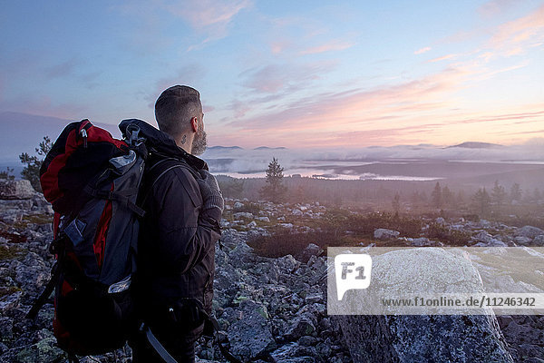 Wanderer genießt den Sonnenuntergang auf dem Gipfel des Sarkitunturi  Lappland  Finnland
