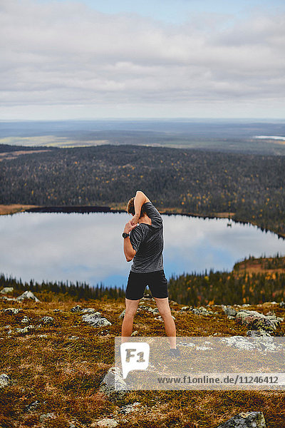 Mann  der sich auf einer felsigen Felsspitze ausdehnt  Keimiotunturi  Lappland  Finnland