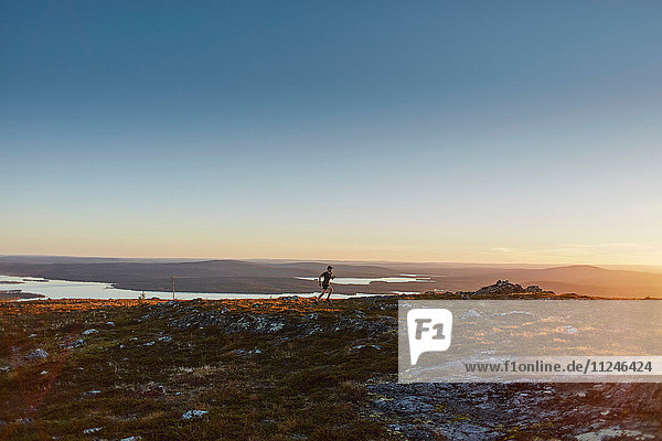 Man running on cliff top at sunset  Keimiotunturi  Lapland  Finland