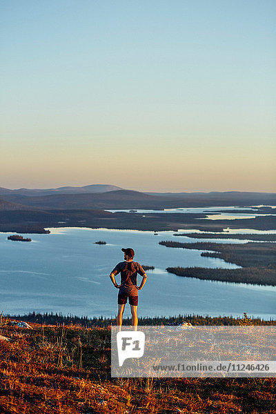 Man looking out to lake on cliff top at sunset  Keimiotunturi  Lapland  Finland