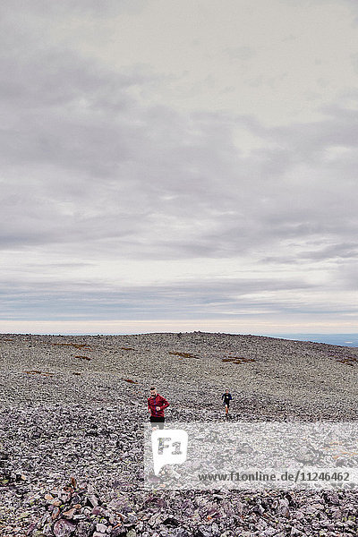 Männer laufen auf felsiger Felsspitze  Kesankitunturi  Lappland  Finnland