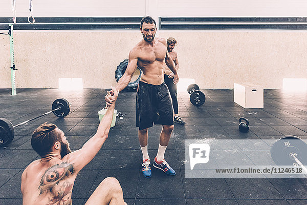 Männlicher Crosstrainer macht eine Wasserpause vom Gewichtheben im Fitnessstudio