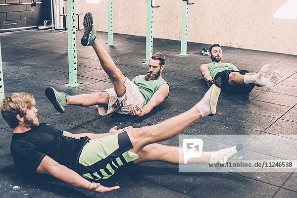 Drei männliche Crosstrainer beim Aufwärmen im Fitnessstudio