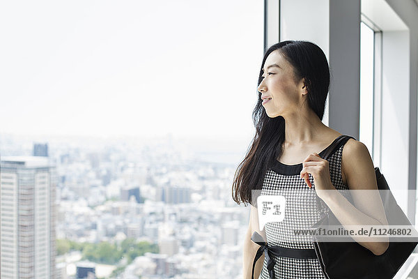A business woman by a window with a view over the city