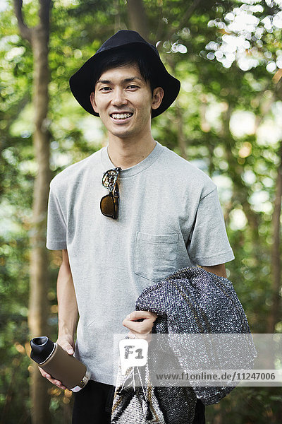 Portrait of a smiling man wearing a hat  standing in a forest.
