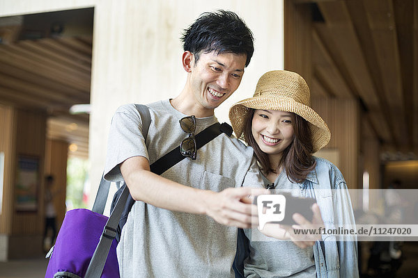 Young woman and man standing outdoors  taking selfie.
