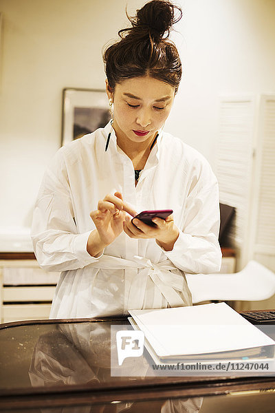 Frau  die in einer Modeboutique in Tokio  Japan  arbeitet und Mobiltelefone benutzt.