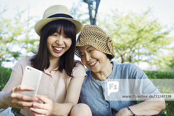Portrait of a smiling senior woman wearing a crochet hat and a young woman wearing a panama hat.