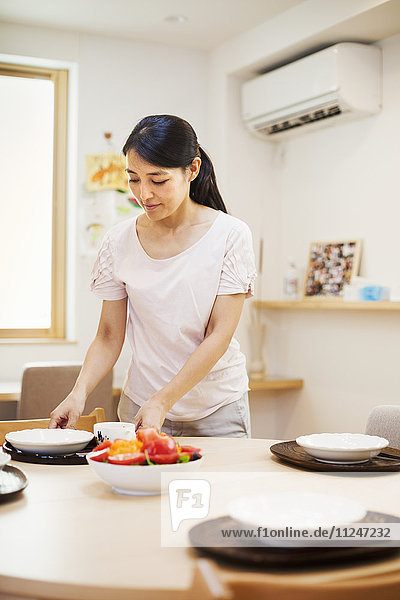 Family home. A woman preparing a meal arranging dishes on a table.