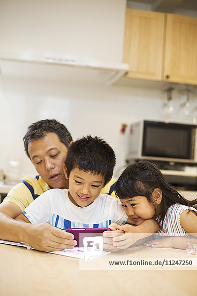Familienhaus. Ein Mann zeigt seinen Kindern den Bildschirm eines Smartphones