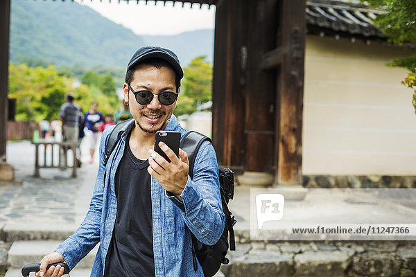 A man in sunglasses looking at his smart phone.