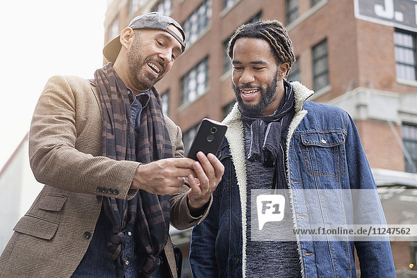 Lächelndes homosexuelles Paar  das ein Selfie mit einem Smartphone auf der Straße macht