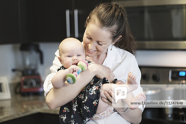 Mutter spielt mit ihrer kleinen Tochter (2-5 Monate) in der Küche