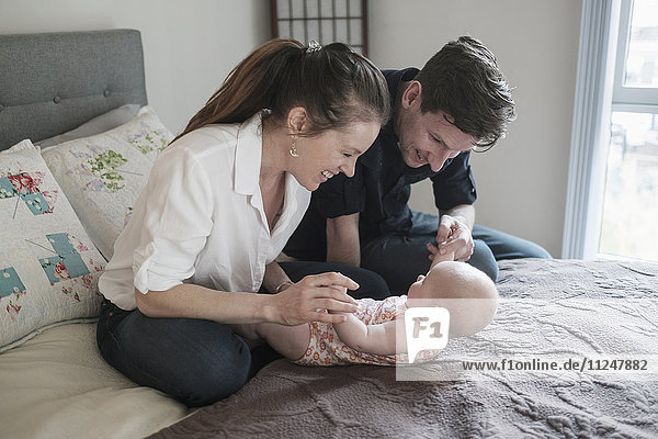 Parents playing with baby daughter (2-5 months) in bedroom